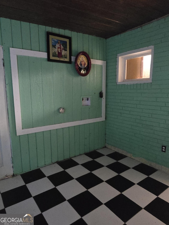 unfurnished room with brick wall and tile patterned floors