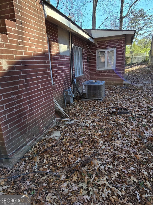 view of side of property with central AC unit and brick siding