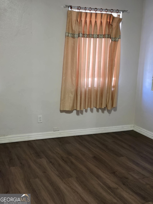 unfurnished room featuring dark wood-type flooring and baseboards