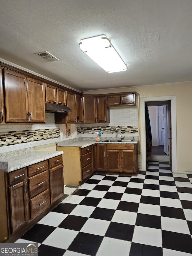 kitchen featuring under cabinet range hood, a sink, visible vents, light countertops, and light floors