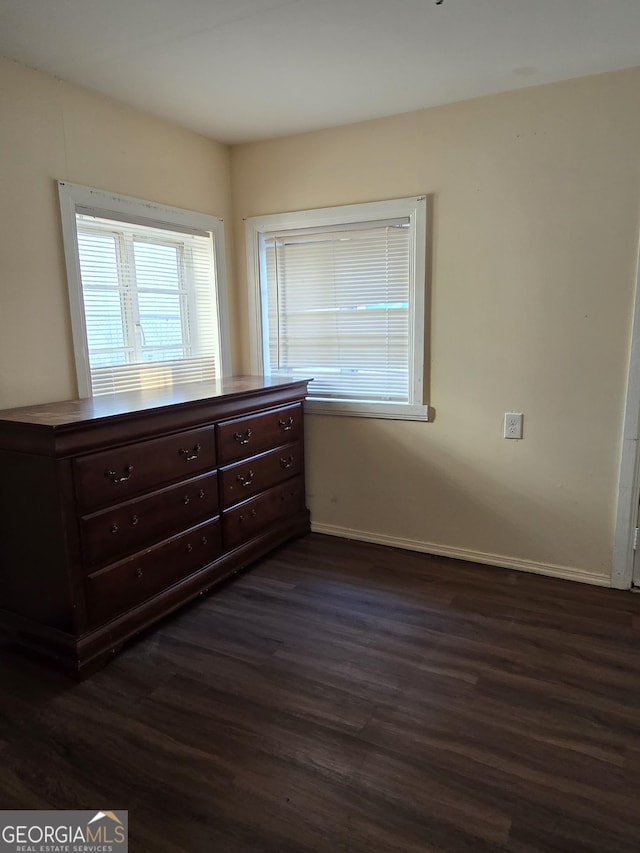 unfurnished bedroom with dark wood finished floors and baseboards