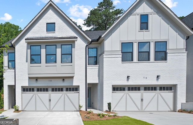 view of front of home with an attached garage, concrete driveway, board and batten siding, and brick siding