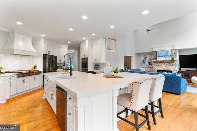 kitchen featuring appliances with stainless steel finishes, a spacious island, custom exhaust hood, and white cabinetry