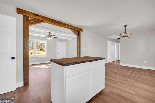 kitchen featuring butcher block countertops, open floor plan, white cabinets, and wood finished floors