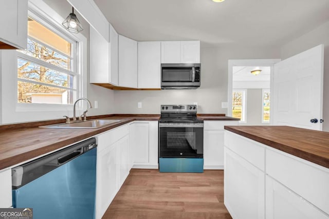 kitchen featuring a sink, white cabinetry, stainless steel appliances, and wooden counters