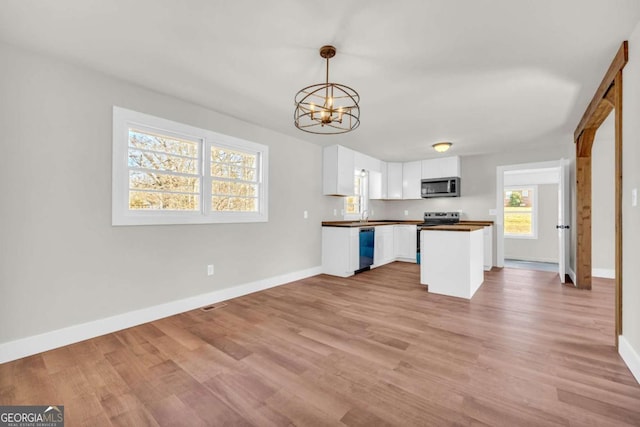 kitchen featuring baseboards, white cabinets, dark countertops, stainless steel appliances, and light wood-type flooring