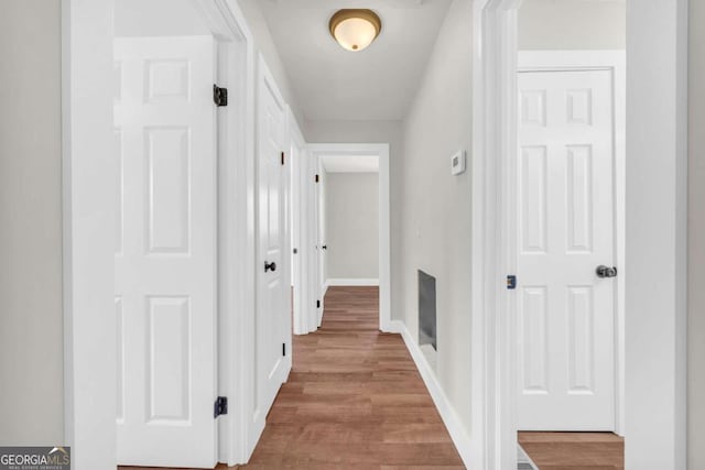 hallway featuring wood finished floors and baseboards