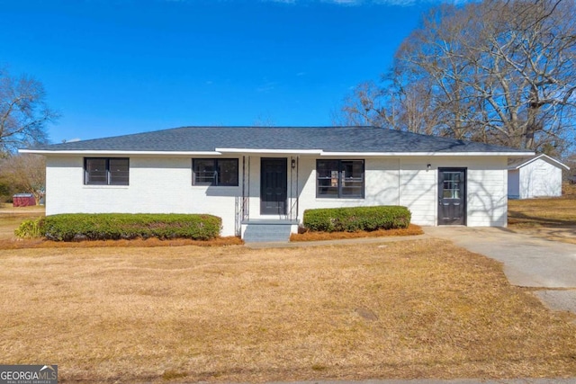 single story home featuring a front lawn, a shingled roof, and brick siding