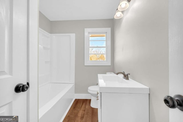 full bathroom featuring toilet, baseboards, wood finished floors, and vanity