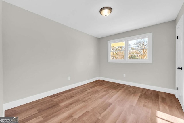 empty room featuring light wood finished floors, visible vents, and baseboards