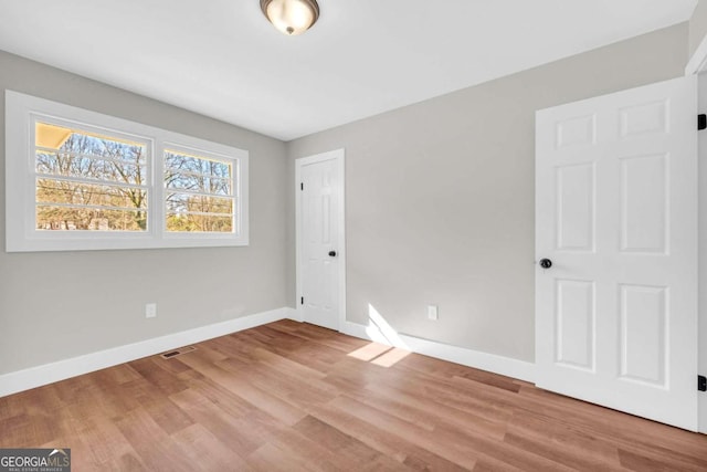 unfurnished bedroom with baseboards, visible vents, and wood finished floors