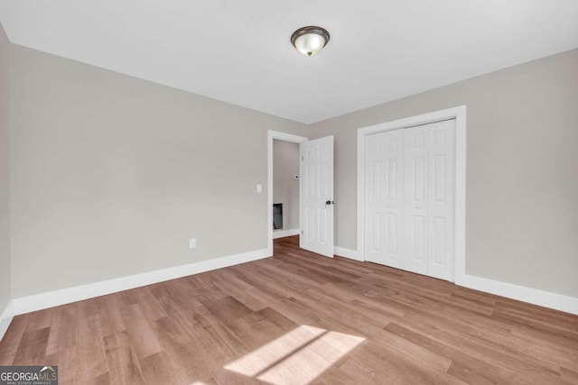 unfurnished bedroom featuring a closet, baseboards, and wood finished floors