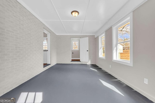 interior space featuring concrete flooring, brick wall, and baseboards