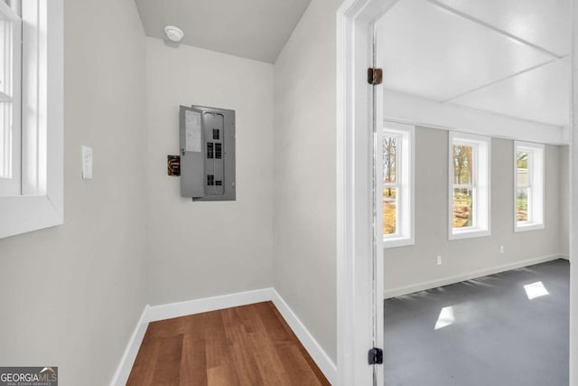 hall featuring dark wood-style flooring, electric panel, and baseboards