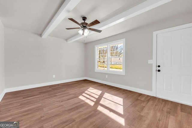 interior space featuring beam ceiling, baseboards, and wood finished floors