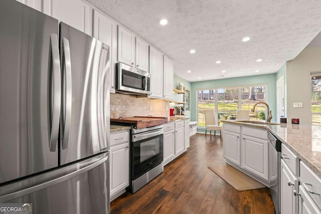 kitchen featuring stainless steel appliances, backsplash, a sink, and white cabinetry