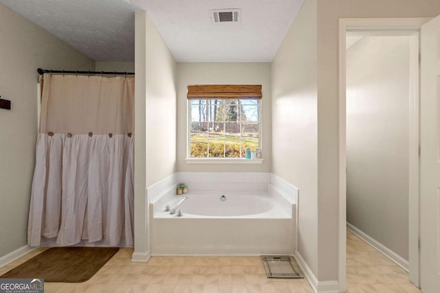 bathroom with a garden tub, visible vents, a textured ceiling, and tile patterned floors