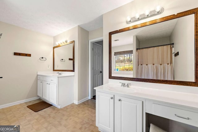 bathroom with a textured ceiling, vanity, baseboards, and tile patterned floors