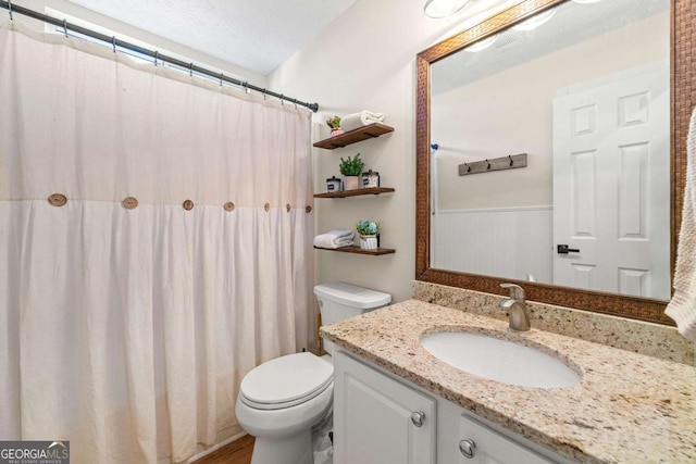 bathroom featuring toilet, a wainscoted wall, and vanity