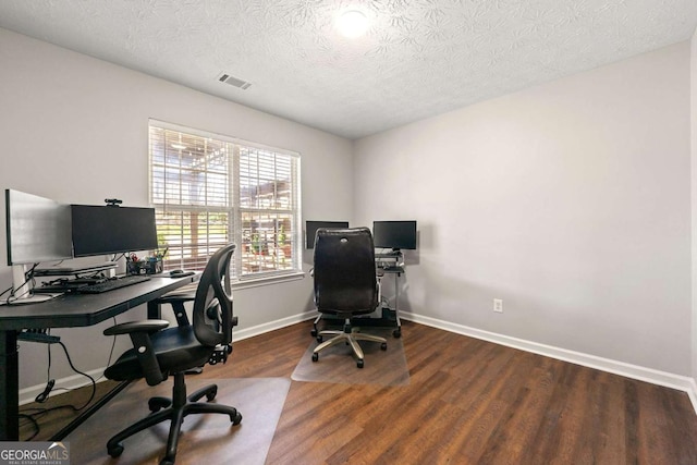 home office with visible vents, a textured ceiling, baseboards, and wood finished floors