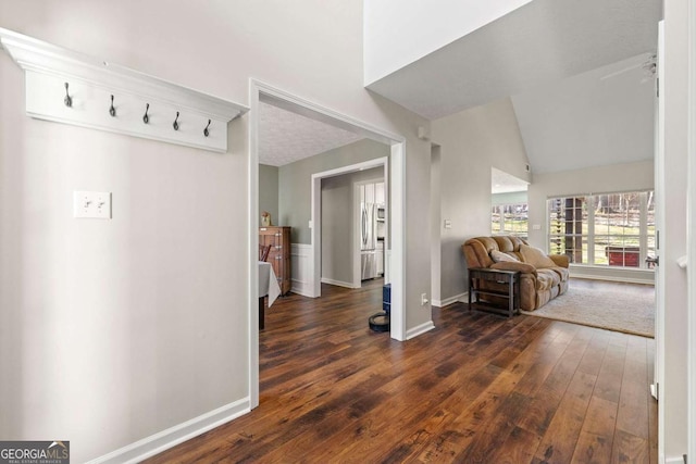 hallway with lofted ceiling, hardwood / wood-style floors, and baseboards