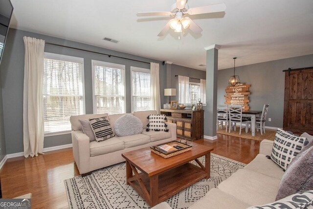 living area featuring baseboards, light wood finished floors, visible vents, and a ceiling fan