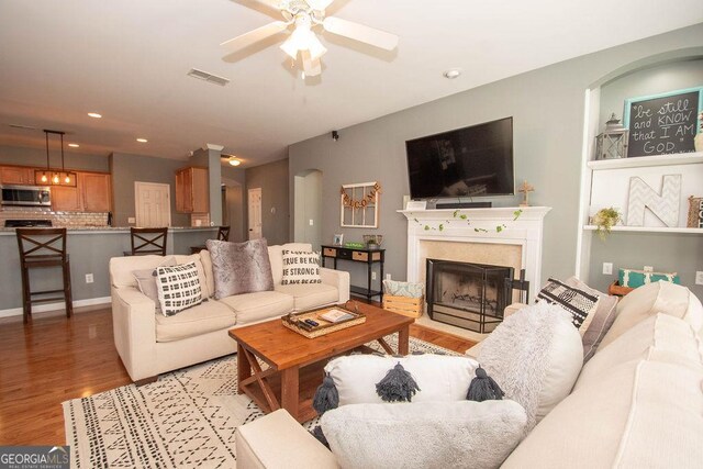 living room featuring light wood finished floors, visible vents, a ceiling fan, a fireplace, and recessed lighting