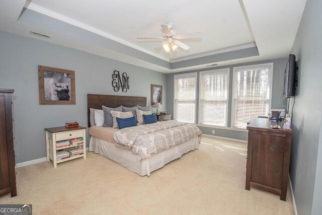 carpeted bedroom featuring ceiling fan, visible vents, baseboards, a raised ceiling, and crown molding