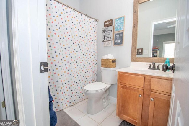 bathroom with a shower with curtain, vanity, toilet, and tile patterned floors