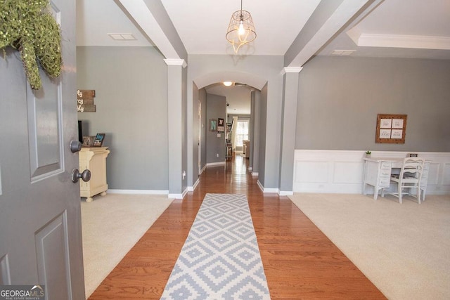 entrance foyer featuring visible vents, arched walkways, wood finished floors, carpet floors, and a decorative wall