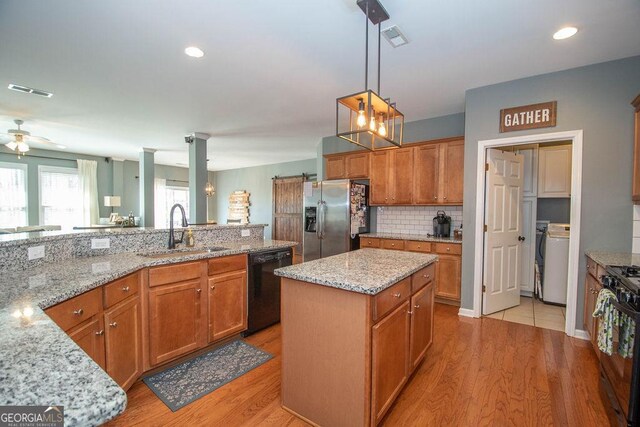 kitchen featuring black appliances, a sink, visible vents, and light wood-style floors