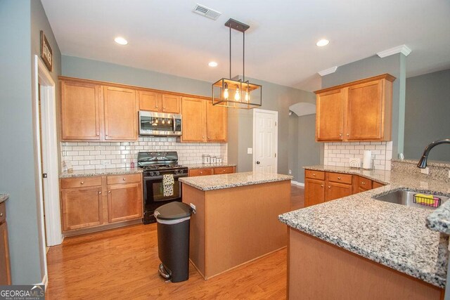 kitchen featuring black range with gas cooktop, a sink, visible vents, light wood-type flooring, and stainless steel microwave