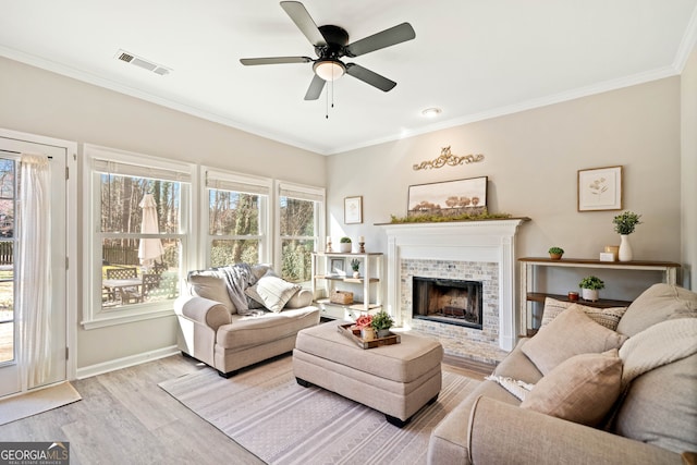 living area featuring wood finished floors, baseboards, visible vents, a fireplace with raised hearth, and ornamental molding