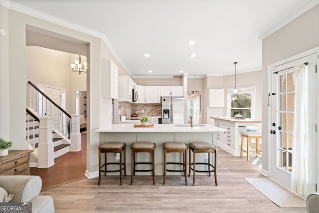 kitchen featuring a peninsula, tasteful backsplash, stainless steel fridge, and light wood finished floors