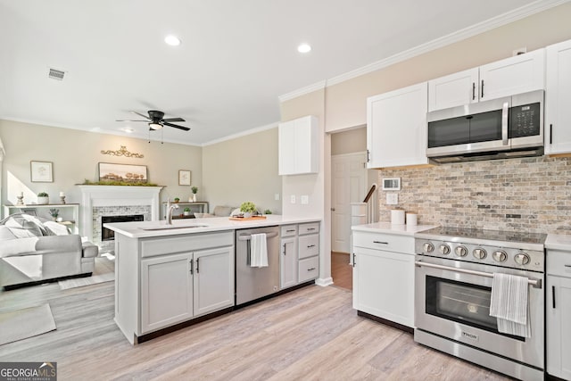 kitchen featuring visible vents, a sink, stainless steel appliances, a peninsula, and a fireplace