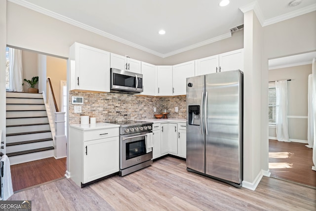 kitchen with white cabinetry, light countertops, light wood-type flooring, and stainless steel appliances