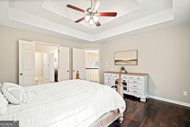 bedroom with ceiling fan, a tray ceiling, baseboards, and hardwood / wood-style floors