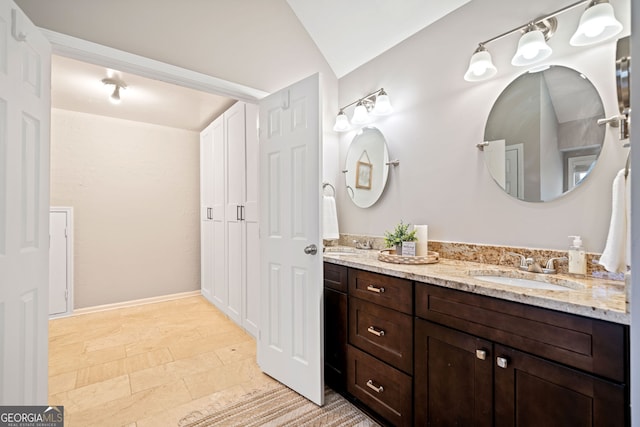 full bath featuring double vanity, lofted ceiling, and a sink