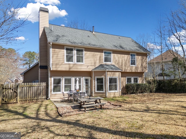 back of house featuring fence, a yard, a shingled roof, a chimney, and a patio area