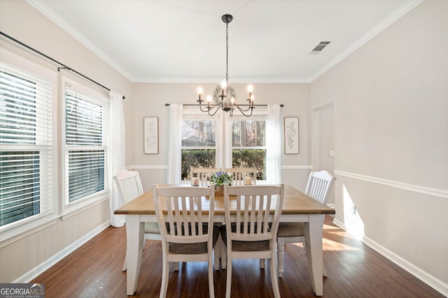 dining room with a notable chandelier, baseboards, visible vents, and wood finished floors