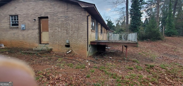 view of side of home with brick siding, entry steps, and a wooden deck