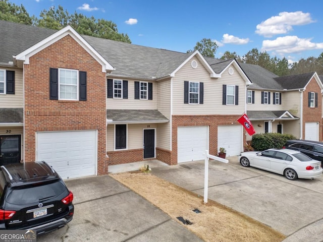 view of property featuring driveway, an attached garage, roof with shingles, and brick siding