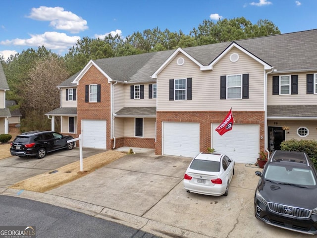 multi unit property with a garage, driveway, brick siding, and roof with shingles