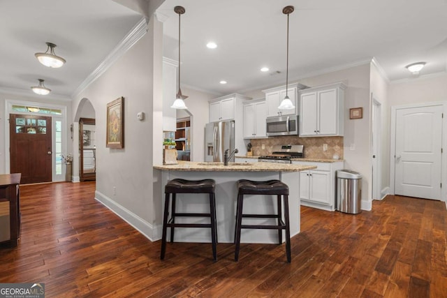 kitchen featuring tasteful backsplash, arched walkways, light stone counters, a breakfast bar, and stainless steel appliances