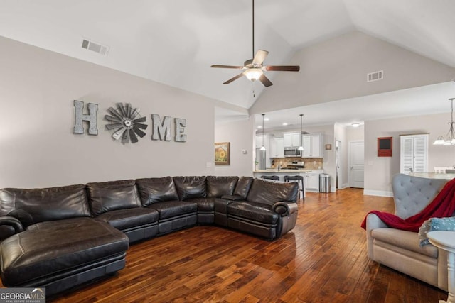 living room featuring dark wood-type flooring, visible vents, high vaulted ceiling, and ceiling fan with notable chandelier