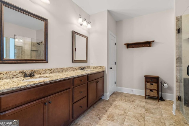 full bath with double vanity, a stall shower, baseboards, and a sink