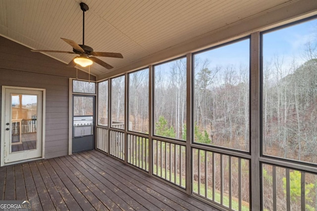 unfurnished sunroom featuring lofted ceiling, ceiling fan, a forest view, and wood ceiling