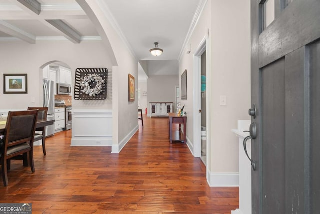 foyer entrance with arched walkways, ornamental molding, dark wood finished floors, and baseboards