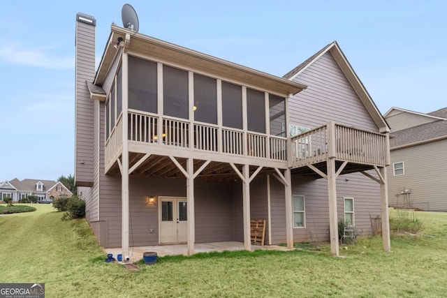 back of house with french doors, a yard, a chimney, a sunroom, and a patio area