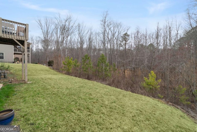 view of yard featuring a wooded view and a wooden deck